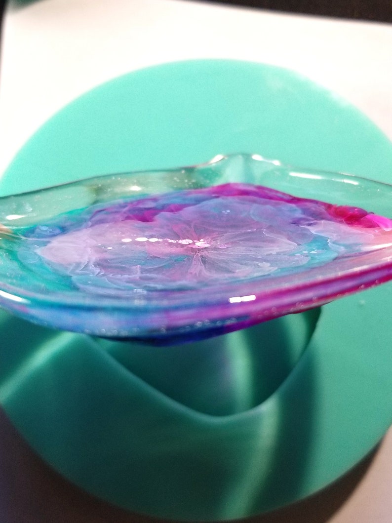May include: A clear resin tray with a swirling pattern of pink, blue, and white. The tray is sitting on a teal surface.