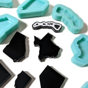 May include: A set of silicone molds in the shape of different states. The molds are light blue and black. The molds are perfect for making resin crafts.