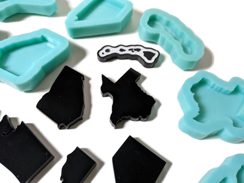 May include: A set of silicone molds in the shape of different states. The molds are light blue and black. The molds are perfect for making resin crafts.