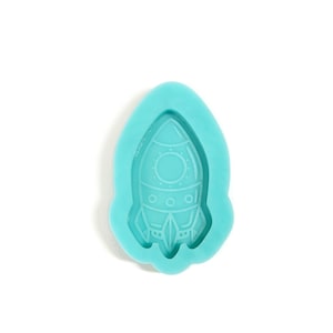 May include: A light blue silicone mold shaped like a rocket ship. The mold is designed to create a resin or polymer clay rocket ship charm.