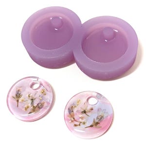 May include: A light purple silicone mold with two circular cavities and a small peg in each. Two clear, round resin pendants with dried flowers and a hole for hanging are also shown.