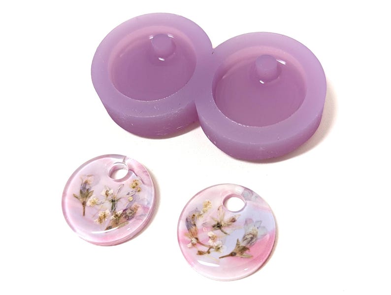 May include: A light purple silicone mold with two circular cavities and a small peg in each. Two clear, round resin pendants with dried flowers and a hole for hanging are also shown.