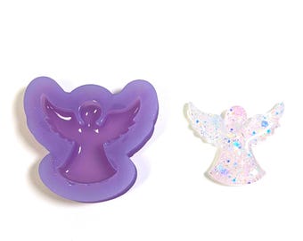May include: A purple silicone angel mould next to a finished angel figurine. The mould is a darker shade of purple, and the figurine is clear with iridescent glitter. Both items are on a white background.