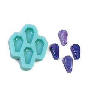 May include: A teal silicone mould with four coffin-shaped cavities. Five purple and blue resin castings in the shape of coffins are shown next to the mould.