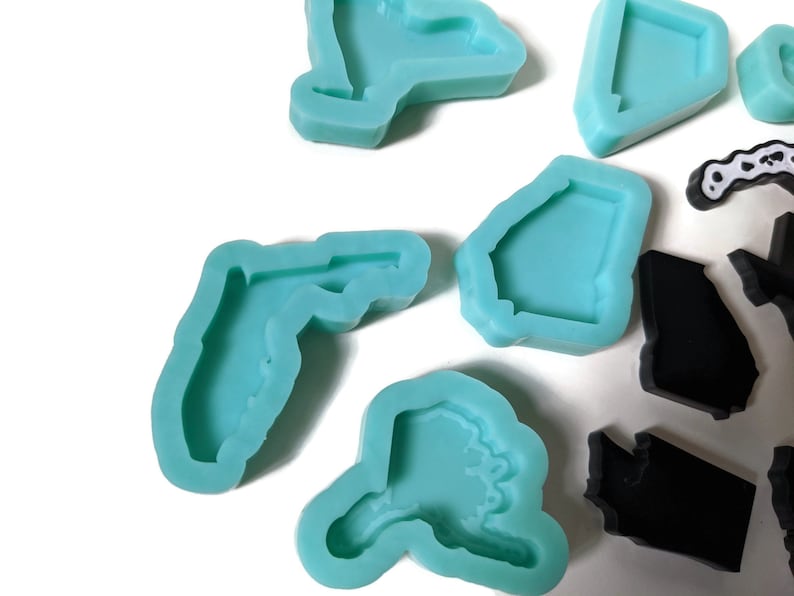 May include: A set of silicone molds in the shape of different states. The molds are light blue and are arranged on a white surface.