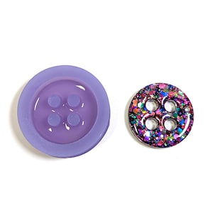 May include: Two buttons on a white background. One is a solid lavender colour with four holes. The other button is round with a glittery, multi-coloured design and four holes. Both buttons are round.