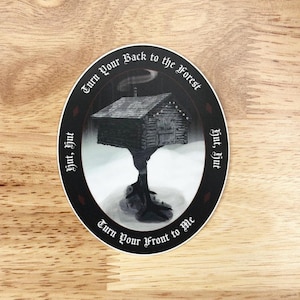 May include: An oval sticker featuring a detailed illustration of a cabin perched atop a tree trunk. The cabin has a gray roof and a smoking chimney. The text "Turn Your Back to the Forest" and "Turn Your Front to Me" are in a circular pattern.