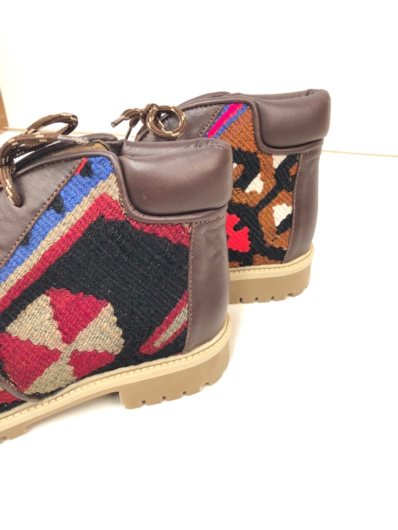 May include: A pair of brown leather ankle boots with colorful woven fabric panels. The boots have a lace-up closure and a chunky sole.