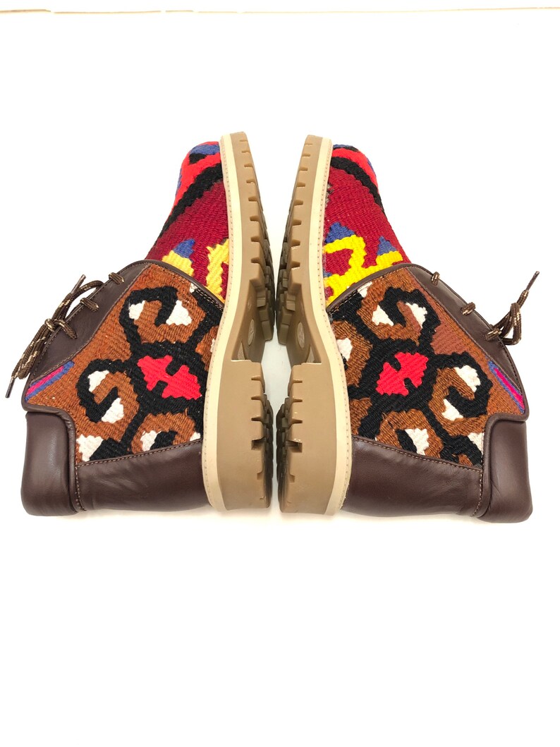 May include: A pair of brown leather ankle boots with colorful patterned fabric uppers. The fabric features a geometric design in shades of red, blue, yellow, and white.