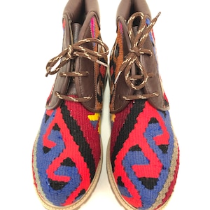 May include: A pair of brown leather ankle boots with colorful patterned fabric uppers. The fabric is a mix of red, blue, black, and yellow.