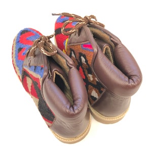 May include: A pair of brown leather ankle boots with colorful woven fabric panels. The boots have laces and a rounded toe.