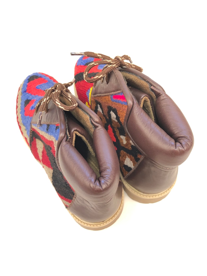 May include: A pair of brown leather ankle boots with colorful woven fabric panels. The boots have laces and a rounded toe.