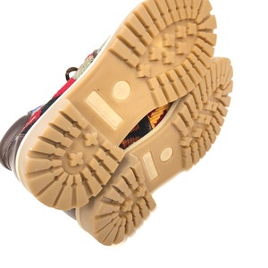 May include: Close-up of the bottom of a pair of brown leather shoes with a colorful patterned fabric upper. The shoes have a brown rubber outsole with a tread pattern.