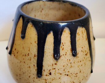 Peut inclure: Une tasse en céramique beige mouchetée avec un glaçage noir qui coule sur les côtés.