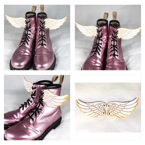 May include: Pink leather boots with black laces and white angel wings attached to the laces. The wings are made of a lightweight material and have a gold outline.