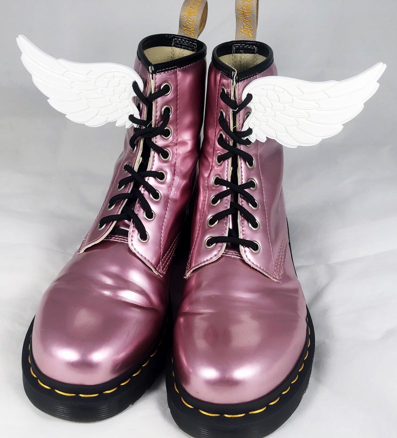 May include: A pair of pink patent leather lace-up boots with white angel wings attached to the laces.