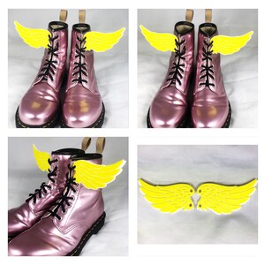 May include: Pink leather boots with yellow wings attached to the laces. The wings are made of felt and have a simple design.