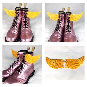 May include: A pair of pink leather boots with gold wings attached to the laces. The wings are a decorative element and are not functional.