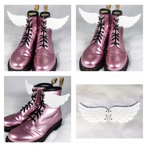 May include: Pink leather boots with white angel wings attached to the laces. The wings are a decorative accessory for the boots.