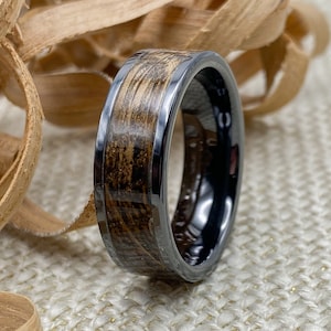 8mm black titanium carbide core with whisky distillery oak inlay of your choice, standing on edge with wood shavings in background