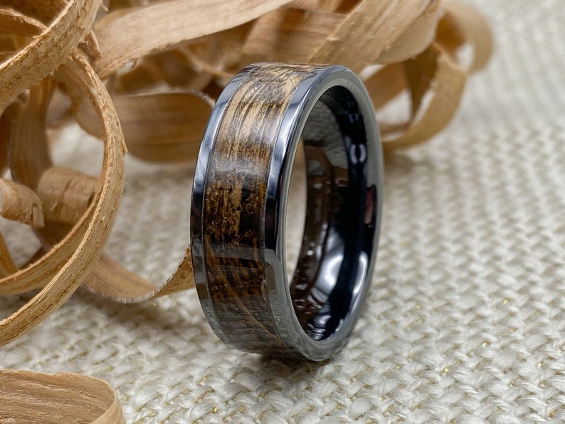 8mm black titanium carbide core with whisky distillery oak inlay of your choice, standing on edge with wood shavings in background