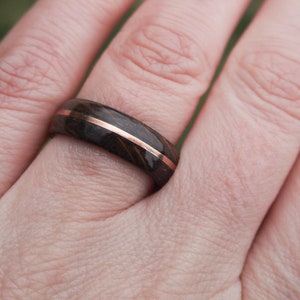 Whisky barrel wedding ring using Lagavulin whisky barrel cask with a centred copper highlight being worn on a feminine presenting ring finger