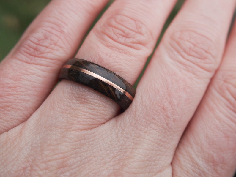 Whisky barrel wedding ring using Lagavulin whisky barrel cask with a centred copper highlight being worn on a feminine presenting ring finger