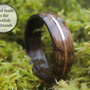 Whisky barrel wedding ring using Lagavulin whisky barrel cask with a centred copper highlight sitting in a bed of moss