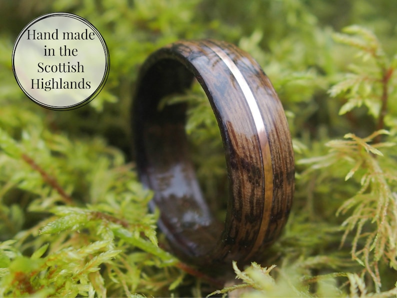 Whisky barrel wedding ring using Lagavulin whisky barrel cask with a centred copper highlight sitting in a bed of moss