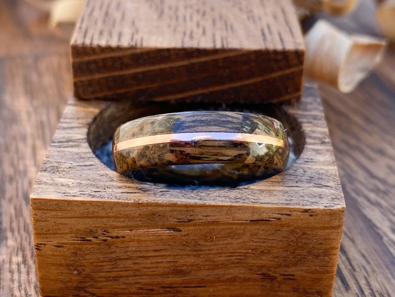 Whisky barrel wedding ring using Lagavulin whisky barrel cask with a centred copper highlight sitting in an oak ring box