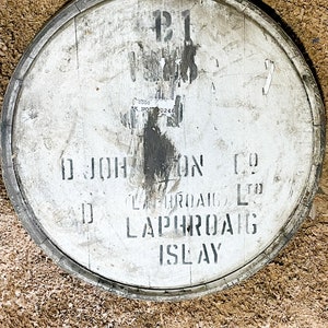Puede incluir: Un barril de madera blanco con letras negras que dicen "D. Johnston & Co. Laphroaig Ltd. Laphroaig Islay". El barril est&aacute; marcado con el n&uacute;mero "121" y una pegatina con el texto "C.D.D.C. BK. NO. 0248".