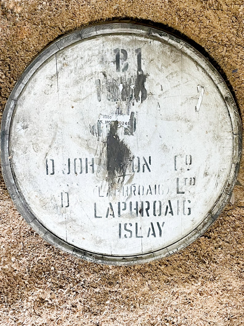 Puede incluir: Un barril de madera blanco con letras negras que dicen "D. Johnston & Co. Laphroaig Ltd. Laphroaig Islay". El barril est&aacute; marcado con el n&uacute;mero "121" y una pegatina con el texto "C.D.D.C. BK. NO. 0248".