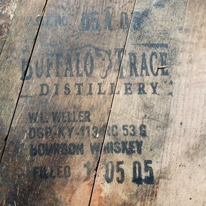 Puede incluir: Primer plano de un barril de madera con letras negras que dicen "Buffalo Trace Distillery", "W.L. Weller", "DSP-KY-113C 53 G", "Bourbon Whiskey" y "Filled 1 05 05".