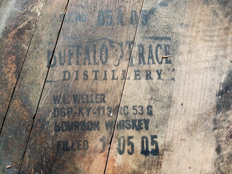 Puede incluir: Primer plano de un barril de madera con letras negras que dicen "Buffalo Trace Distillery", "W.L. Weller", "DSP-KY-113C 53 G", "Bourbon Whiskey" y "Filled 1 05 05".