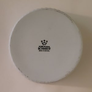May include: White porcelain bowl with a black logo that reads "Porcelana Schmidt Made in Brazil" and a crown above the text.
