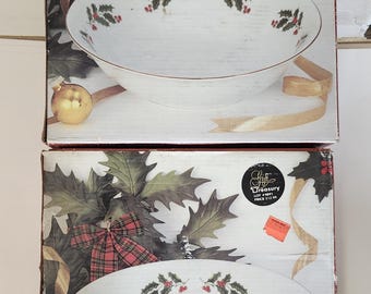 May include: Two white ceramic serving bowls with a gold rim and holly berry design. The bowls are in their original boxes, which feature a Christmas theme with holly, ribbons, and a plaid bow.