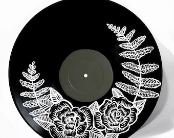 May include: A black vinyl record with a white floral design painted on it. The design features roses and ferns.