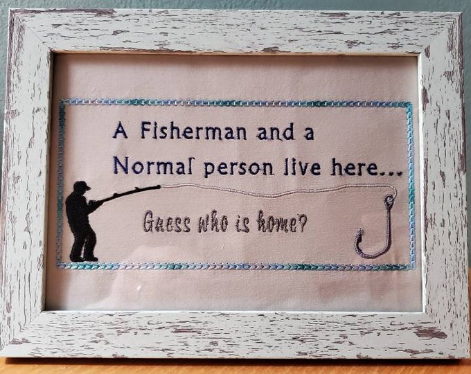 Un pêcheur et une personne normale vivent ici (broderie encadrée)