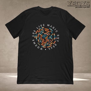May include: Black t-shirt with a colorful graphic design of a circle with the text "Words are like magic but real" around it.