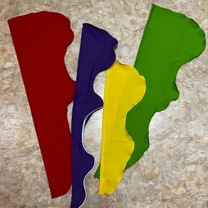 May include: Four fabric strips in red, purple, yellow, and green, each with a scalloped edge. The strips are arranged in a V-shape.