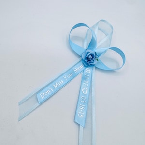 May include: Light blue satin ribbon with a small white flower and the text "Don't Miss Your Show 07.13.57 03.18.15" printed on it.