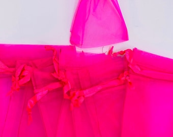 May include: A set of ten pink organza gift bags with satin ribbon ties. The bags are made of sheer fabric and are perfect for small gifts or favors.