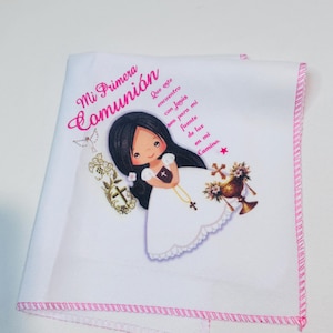 May include: White handkerchief with a pink stitched border, featuring a cartoon illustration of a girl in a white dress. The text "Mi Primera Comunión" is written in pink script, along with additional text.