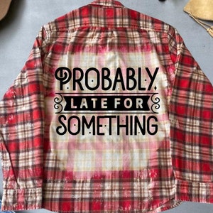May include: Red and black plaid flannel shirt with a bleached effect and the text "Probably Late For Something" printed on the back.