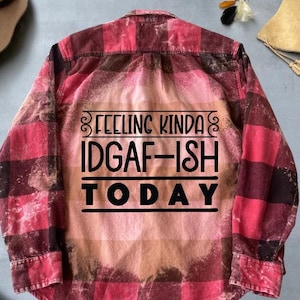 May include: Red and black checked flannel shirt with the text "Feeling Kinda IDGAF-ISH TODAY" printed on the back.