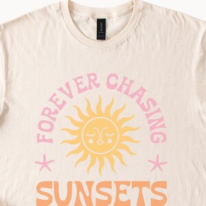 May include: A beige t-shirt with a pink graphic design that says "FOREVER CHASING SUNSETS" with a stylised sun and two stars.