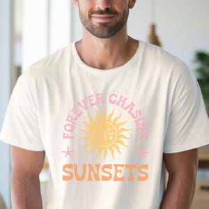 May include: White t-shirt with a pink and orange graphic design featuring a sun with a face and the text "FOREVER CHASING SUNSETS".
