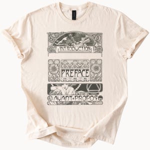 Pode incluir: Camiseta creme com ilustrações e texto em estilo Art Nouveau. O design inclui as palavras "INTRODUCTION", "PREFACE" e "AVANT-PROPOS" em uma fonte decorativa, juntamente com imagens detalhadas em preto e branco.