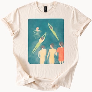 May include: A white t-shirt with a vintage-style illustration of people swimming in a teal blue pool. The illustration features five figures, four of whom are diving into the water. The fifth figure is floating on their back in the water.