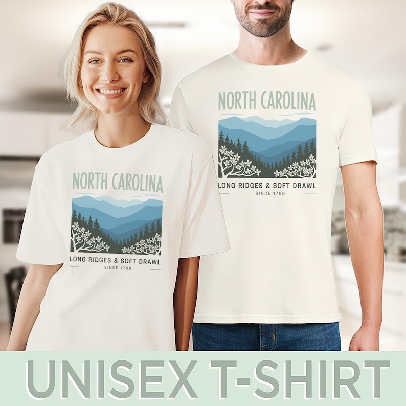 May include: Off-white unisex t-shirts featuring a graphic of the North Carolina mountains. The design includes the text "NORTH CAROLINA", "LONG RIDGES & SOFT DRAWL", and "SINCE 1789". The shirts are worn by two people.